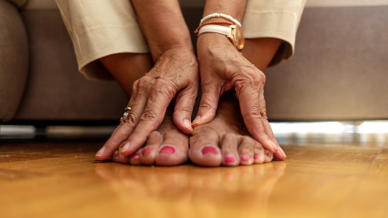 An older woman massages her feet to relieve the pain caused by arthritis
