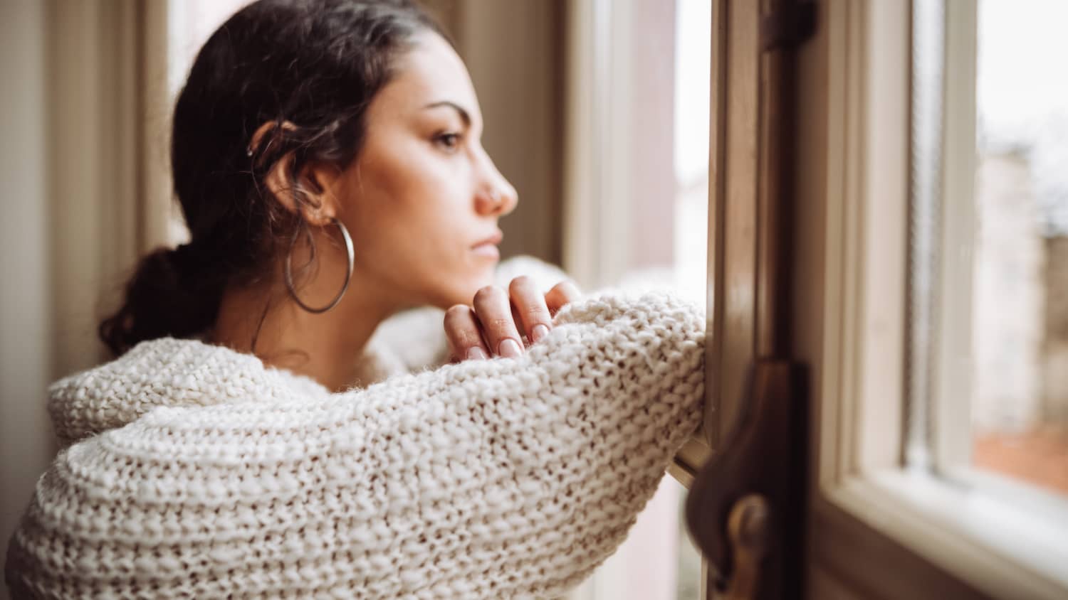 pensive woman in front of the window, thinking about advanced directives, especially amid COVID