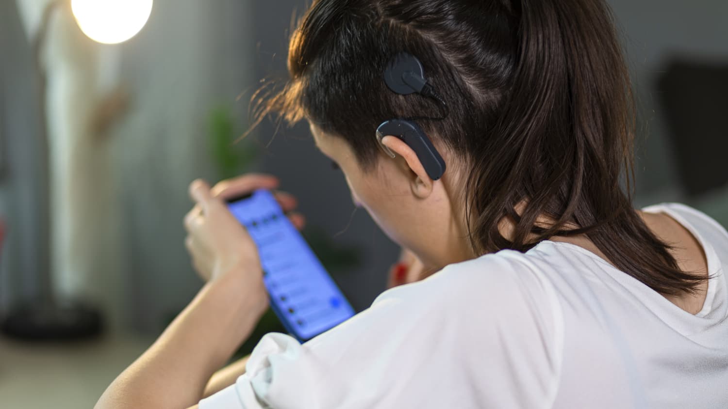 a woman with a cochlear implant scrolls on her phone