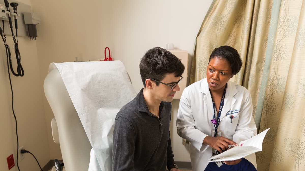 Doctor sits beside a patient in an exam room talking about a possible thyroid cancer diagnosis.