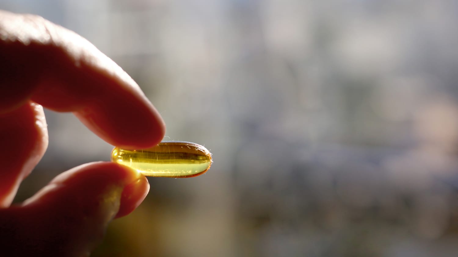 person holding vitamin d capsule