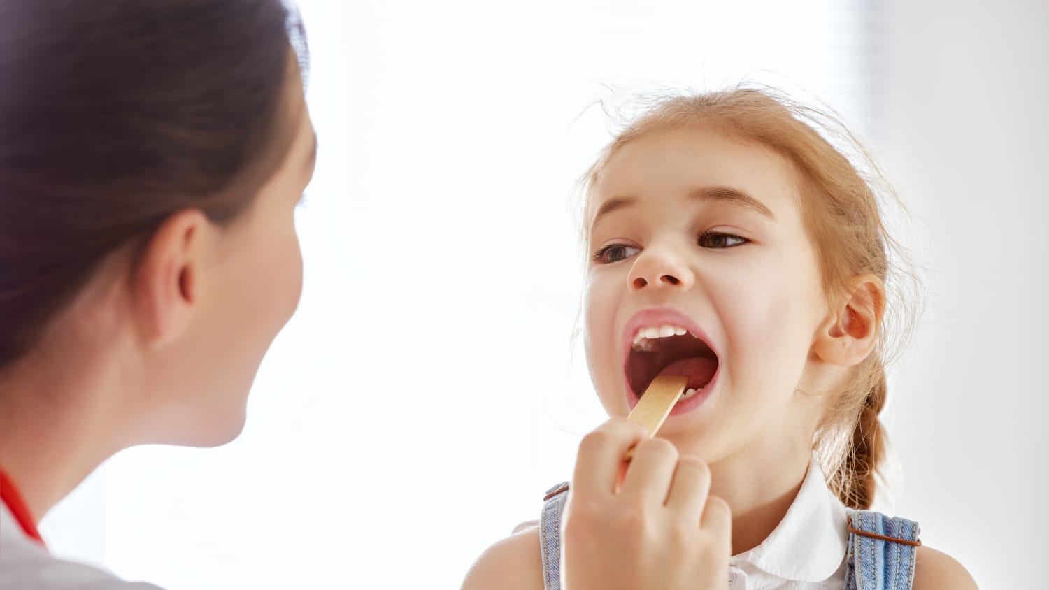 A girl has her throat examined for pediatric tonsillitis.