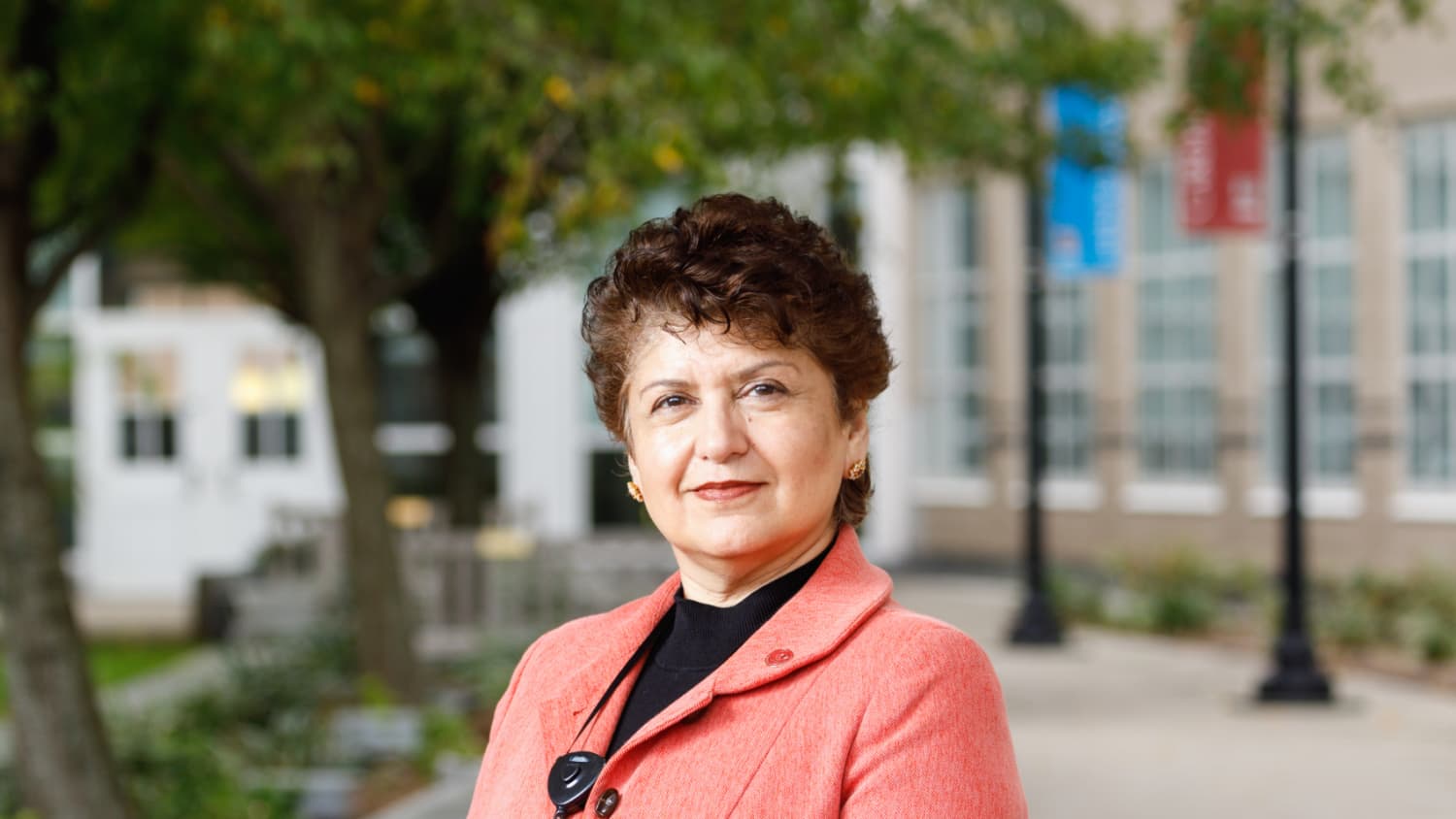 Dr. Lubna Pal portrait photo in outdoor courtyard with trees in the background.