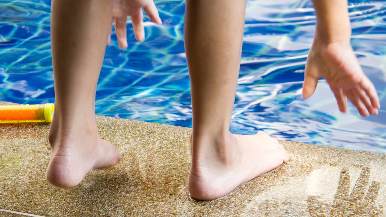 Child at a pool with his feet exposed, possibly leaving him open to harmless but contagious skin conditions.