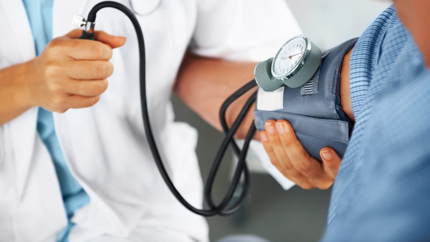 A doctor checks the blood pressure of a patient who may have high cholesterol.