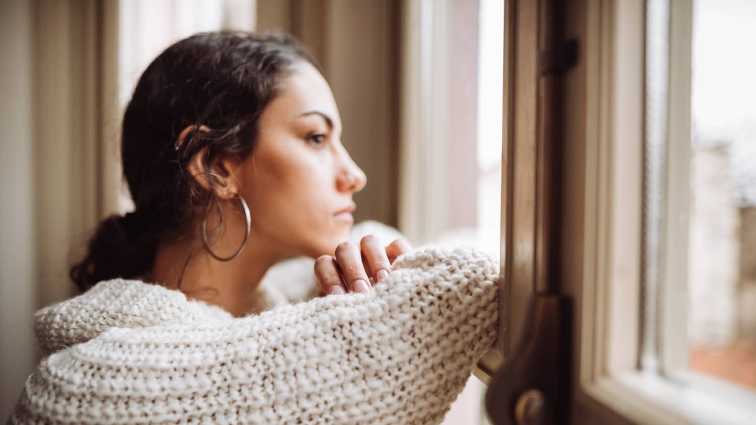 pensive woman in front of the window, thinking about advanced directives, especially amid COVID