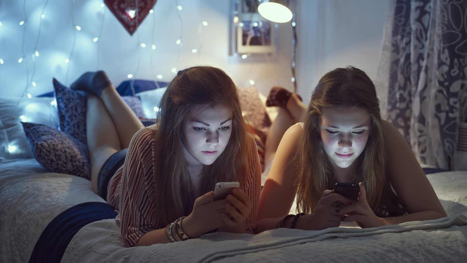 two teenage girls in their room on their phones, representing how social media can affect teens' mental health