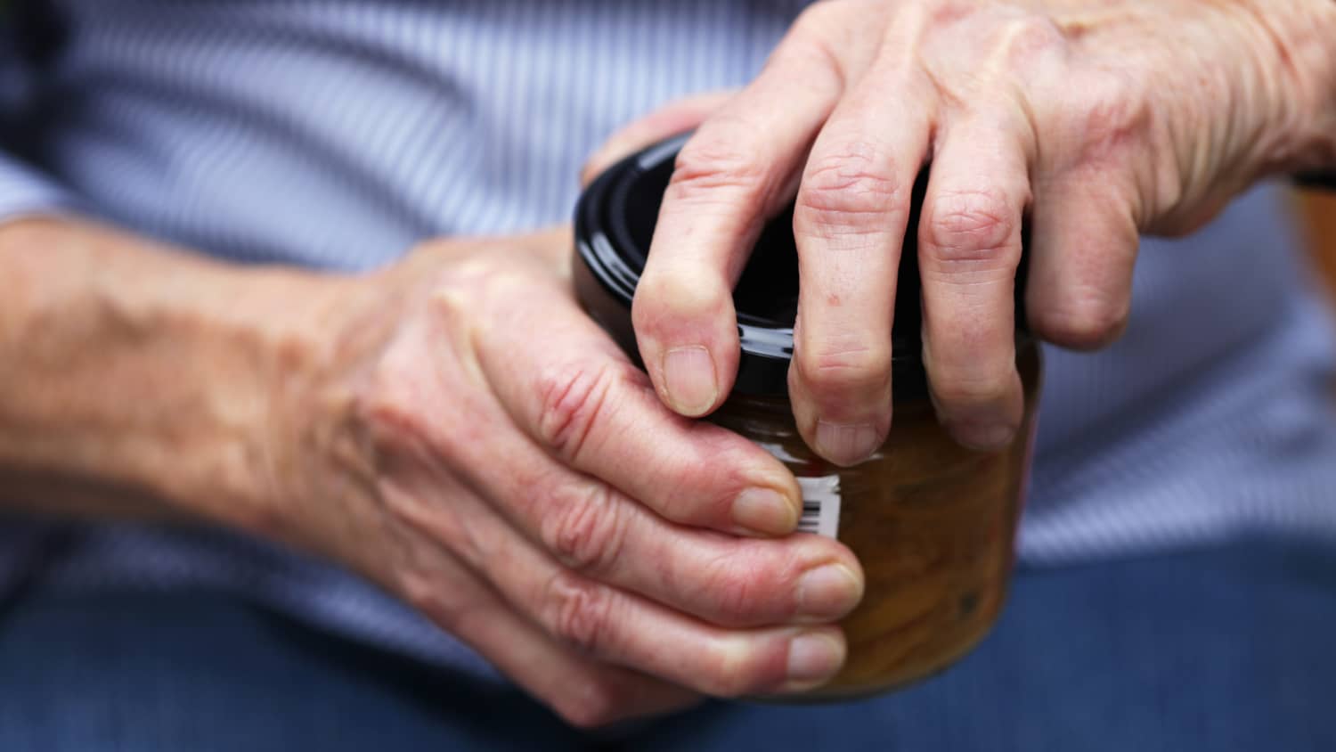 Older person with arthritis having difficulty opening a jar