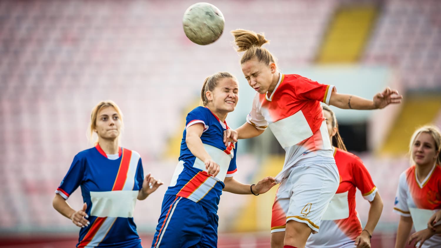 Two female soccer rivals heading the ball on a match, possibly at risk for concussion