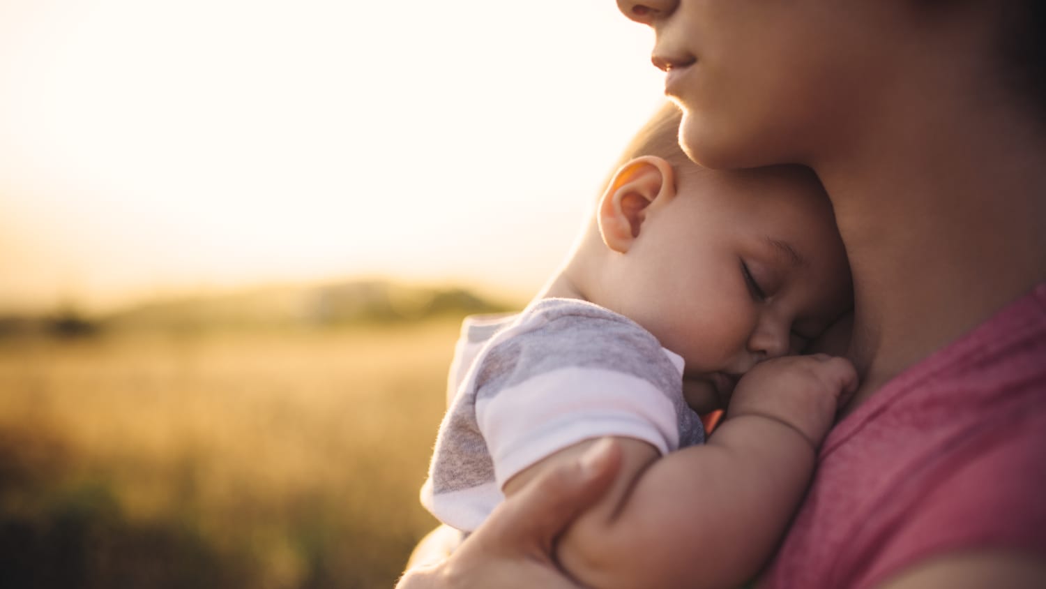 A woman holds her napping son.