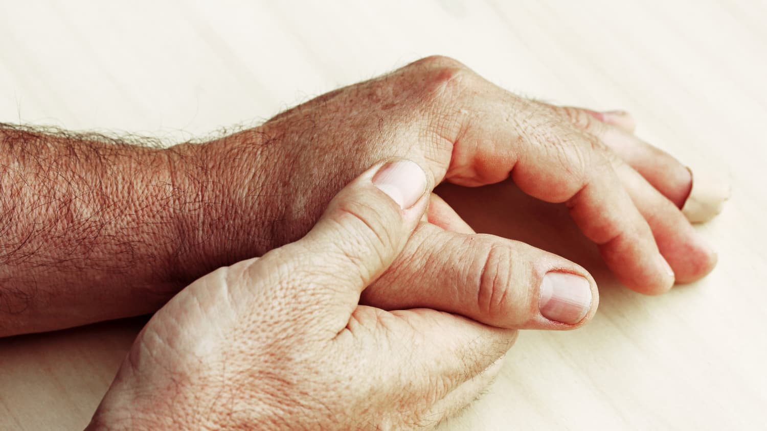 A person massages their hands, possibly because of Dupuytren's syndrome.