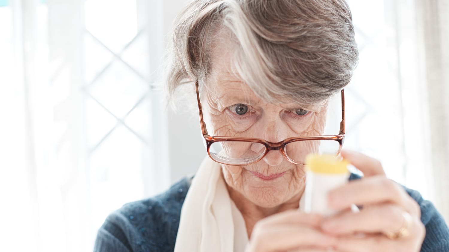 older woman trying to read prescription medication bottle