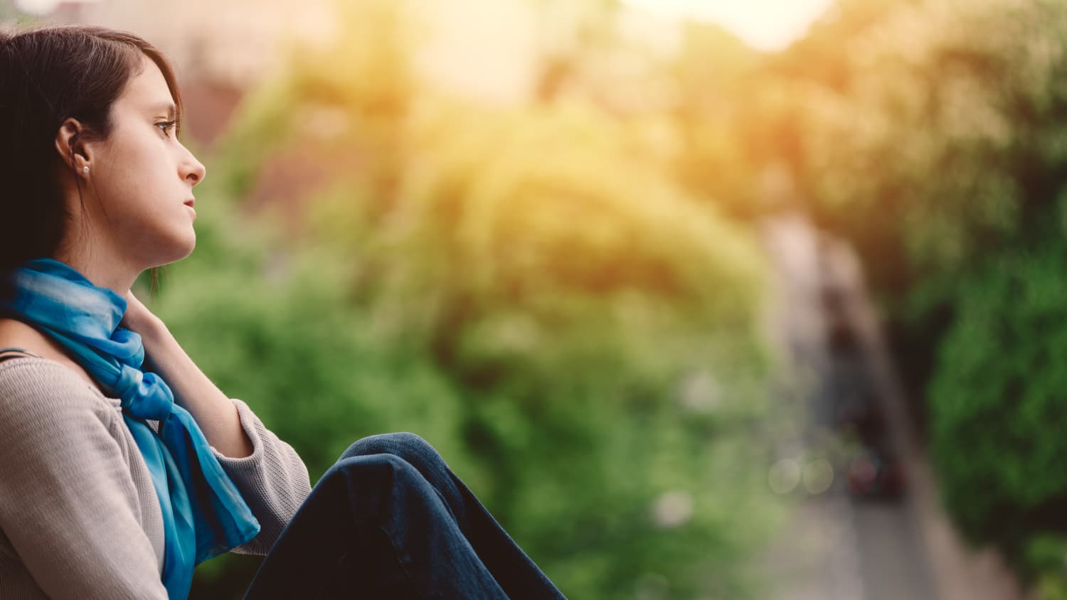 A young woman who is feeling suicidal sits alone outside.