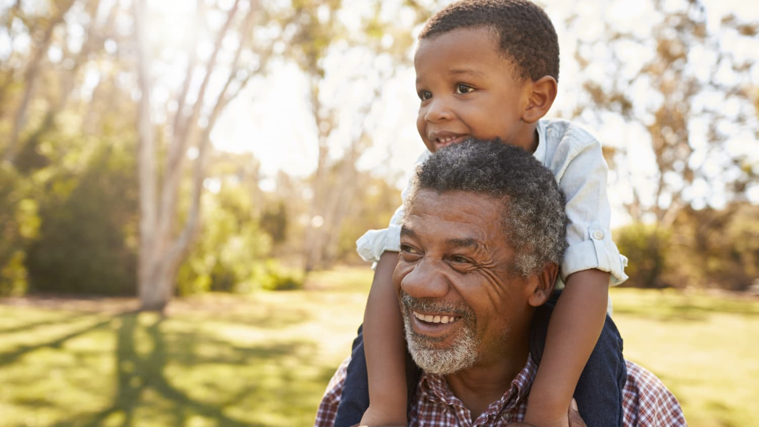 older man smiling with grandson on his shoulder after treatment for Chronic Myeloid Leukemia (CML)