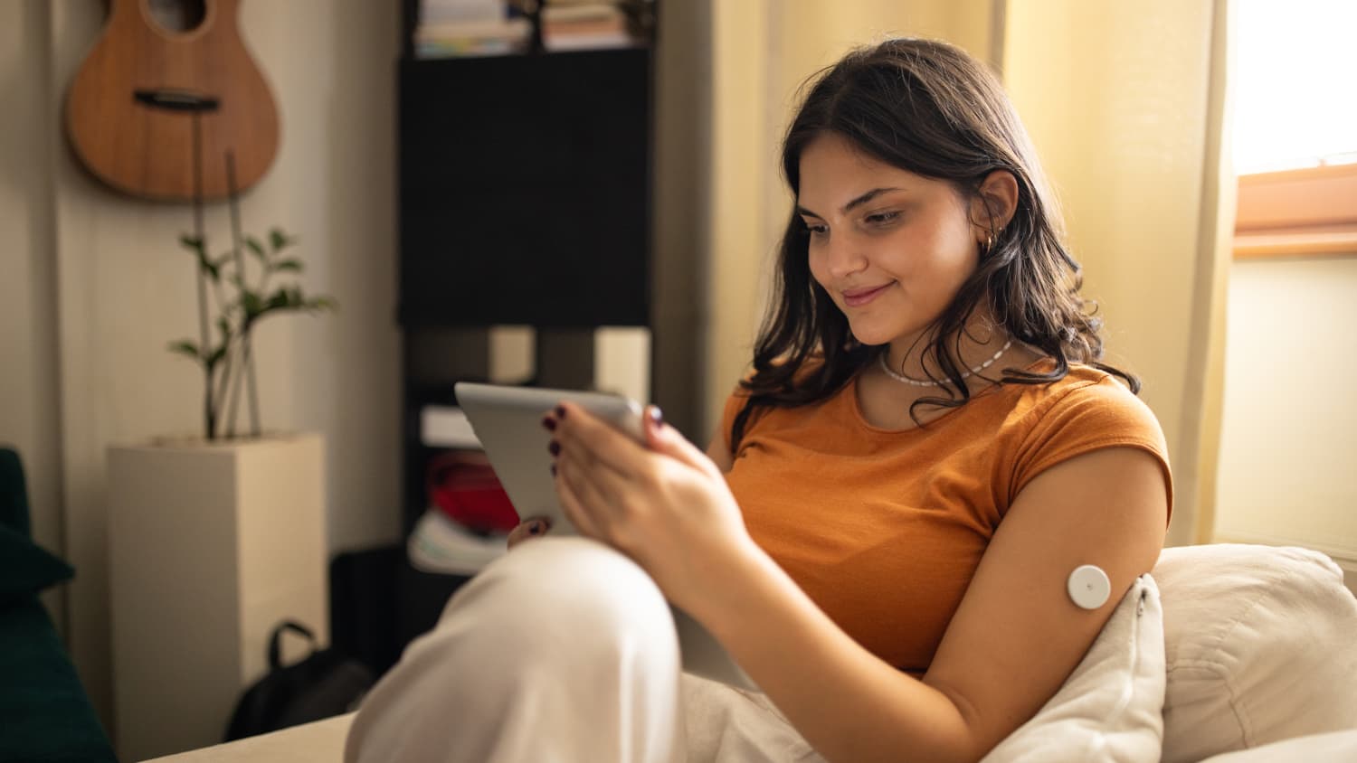 woman with continuous glucose monitor (CGM) on couch