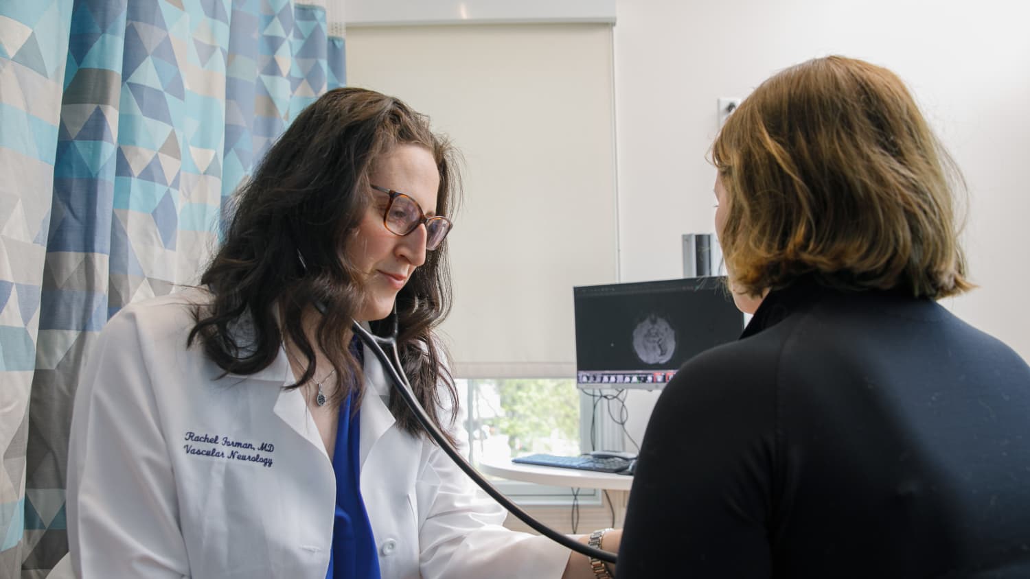 A Yale Medicine physician who specializes in stroke, listens to a female patient's heart in the office. h a female patient in the office,