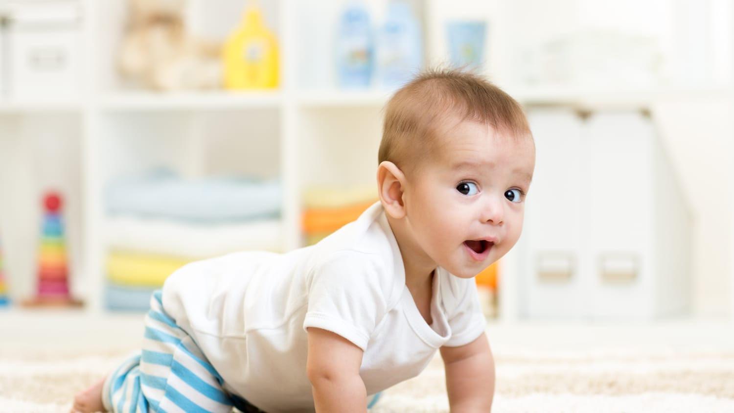 An infant who may have child development issues crawls on the floor.