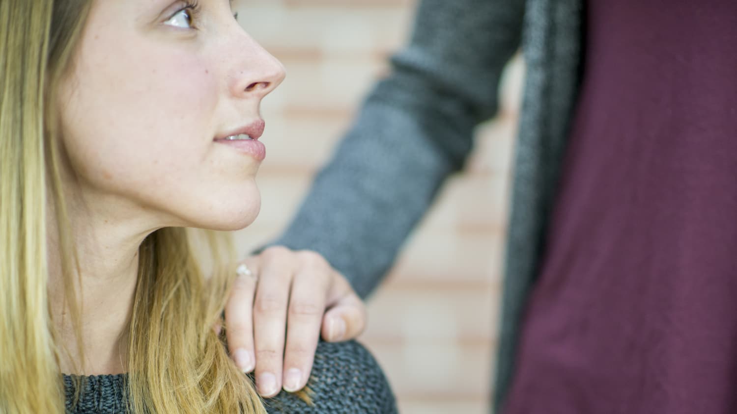 A woman puts her hand on the shoulder of a woman who may be having psychotic symptoms.