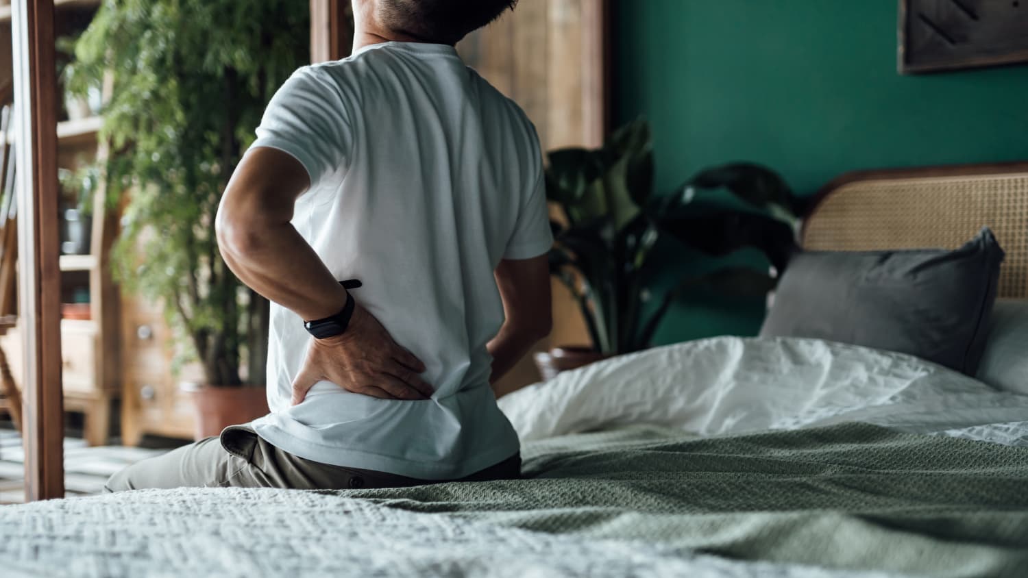 a man with spondylosis in bed rubbing back