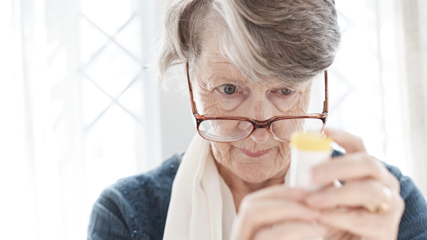 older woman trying to read prescription medication bottle