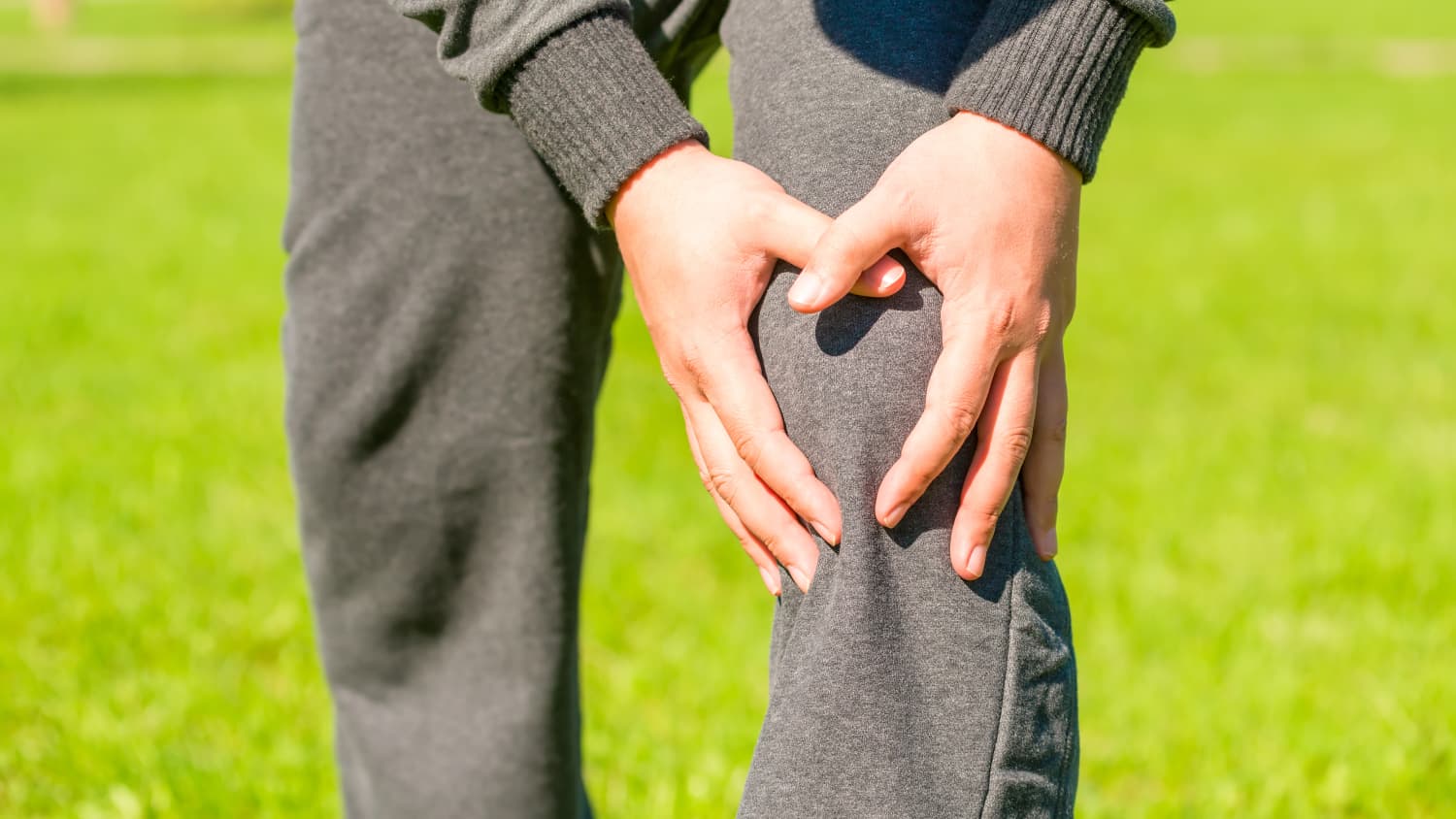 A man grabs his knee, possibly because of knee instability