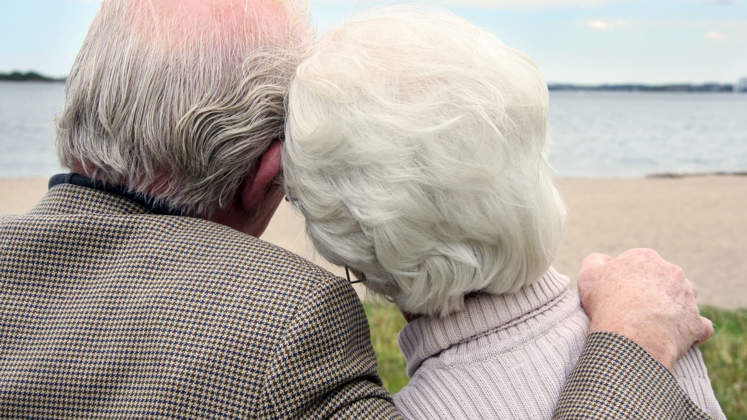 A man who needs reconstructive urethral surgery sits with his wife on a beach.