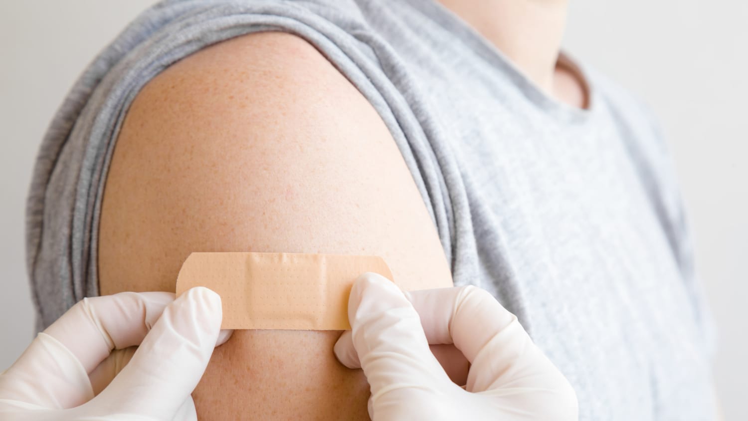 doctor putting bandage on patient after receiving a vaccine