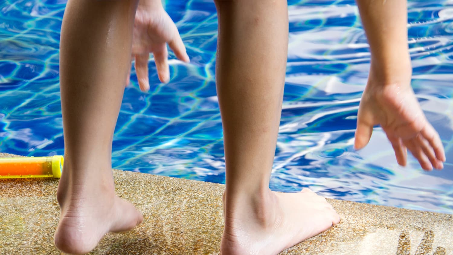 Child at a pool with his feet exposed, possibly leaving him open to harmless but contagious skin conditions.