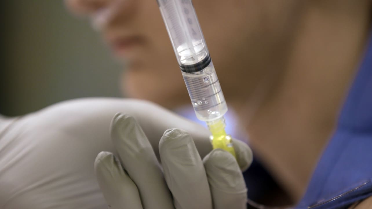 An anesthesiologist checks a syringe.