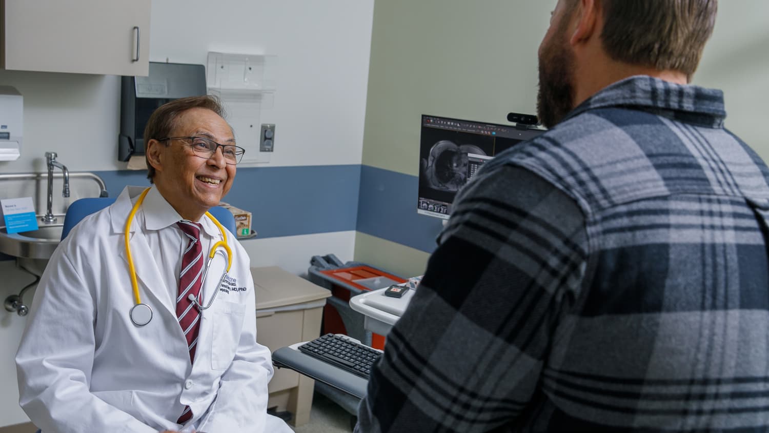 Pramod Mistry, MD, a Yale Medicine physician and Gaucher disease expert, talks to a patient in an exam room.