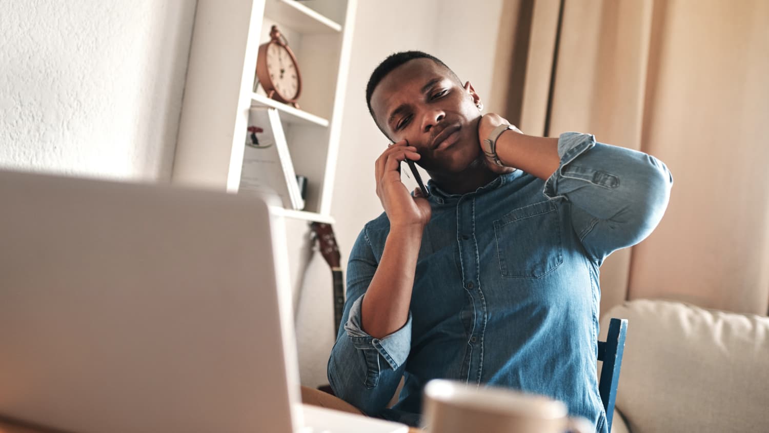 man on a laptop experiencing neck pain, possibly from working from home during COVID-19