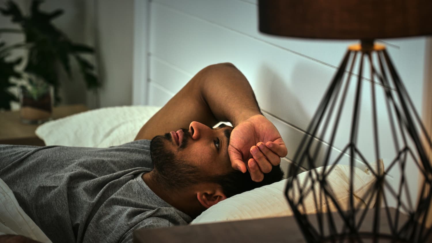 A man lying in bed struggling to sleep
