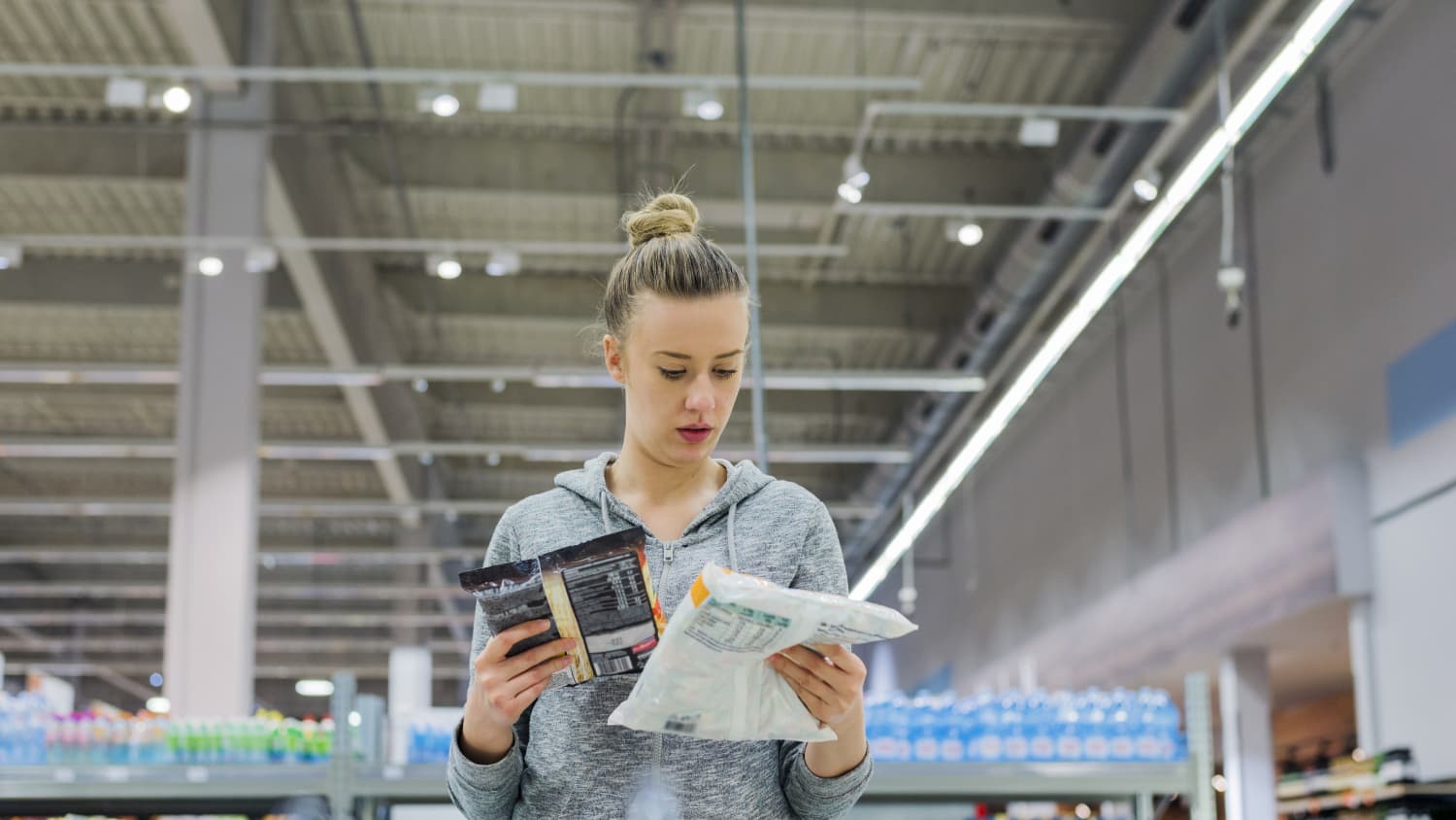 woman looking at food packages in grocery store to see if they're ultraprocessed