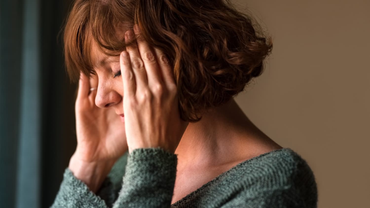 woman experiencing a migraine, putting her hands on her head