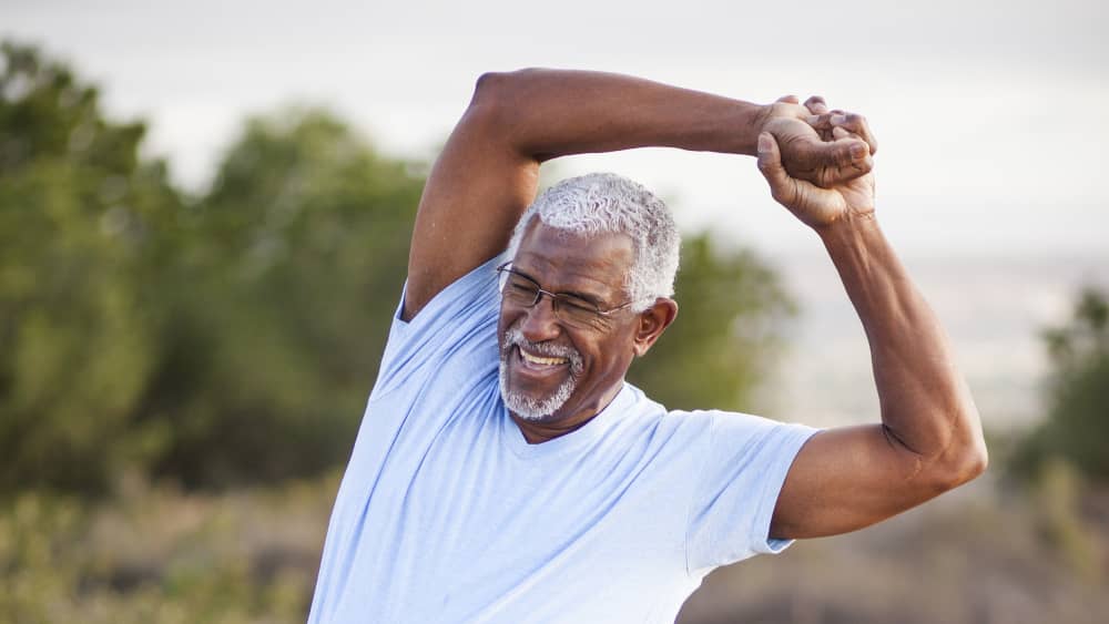 A middle-aged man stretches his back, possibly after artificial disk replacement surgery