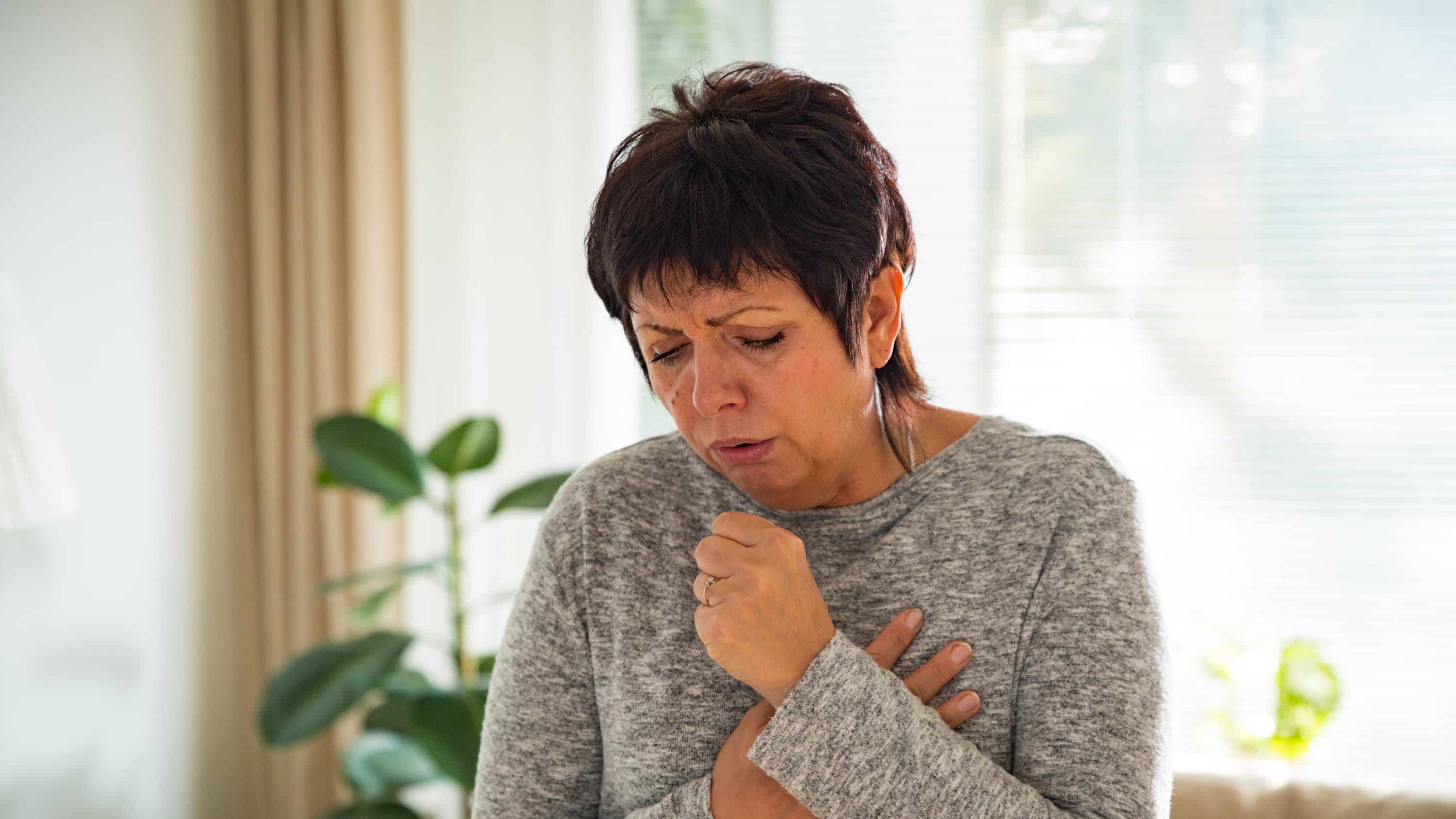woman coughing, possibly because of lung cancer even though she is a non- or never-smoker