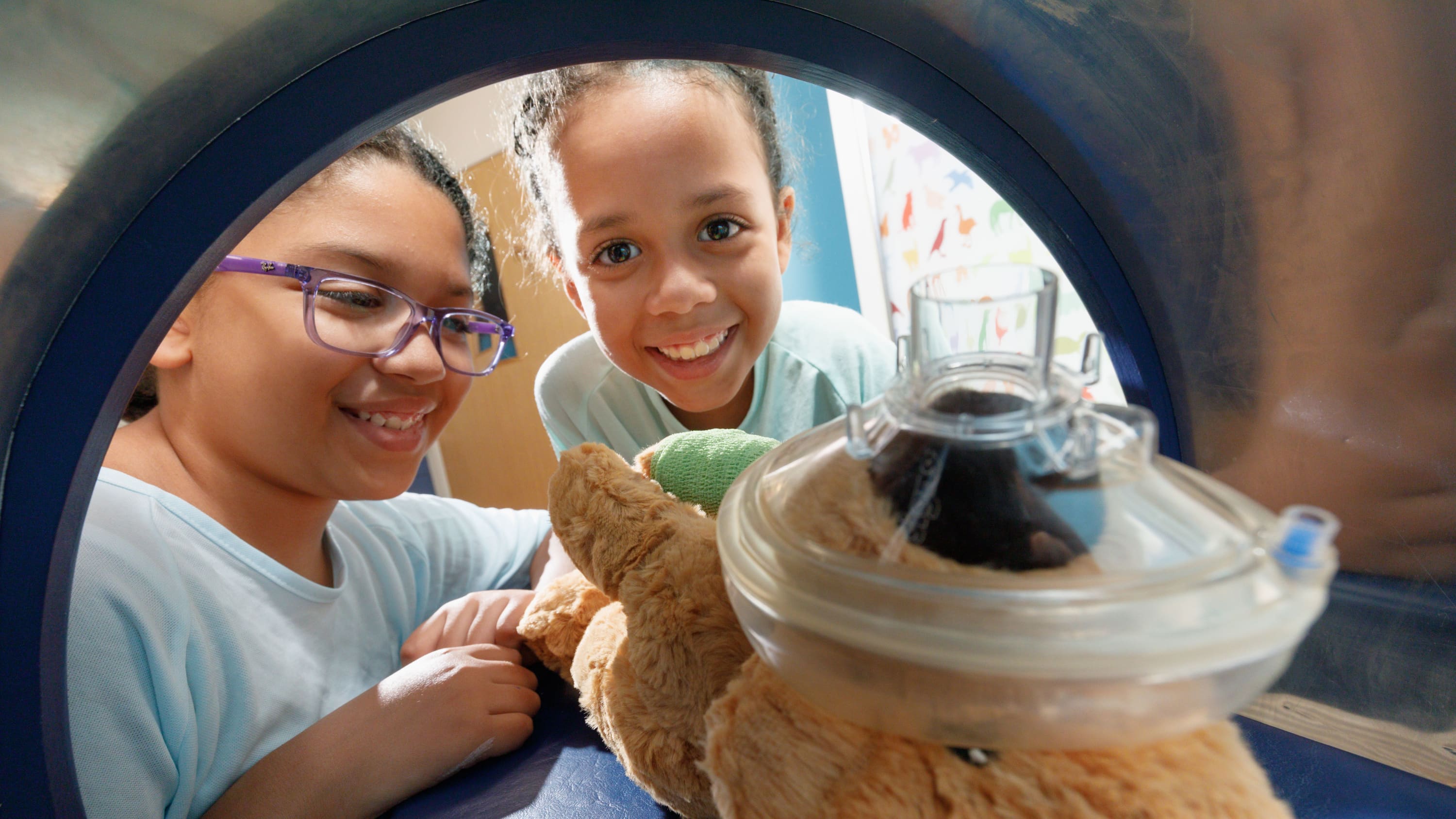 Leila, 8, and older sister Nadia, 10, use a toy MRI scanner on a menagerie of stuffed animals.