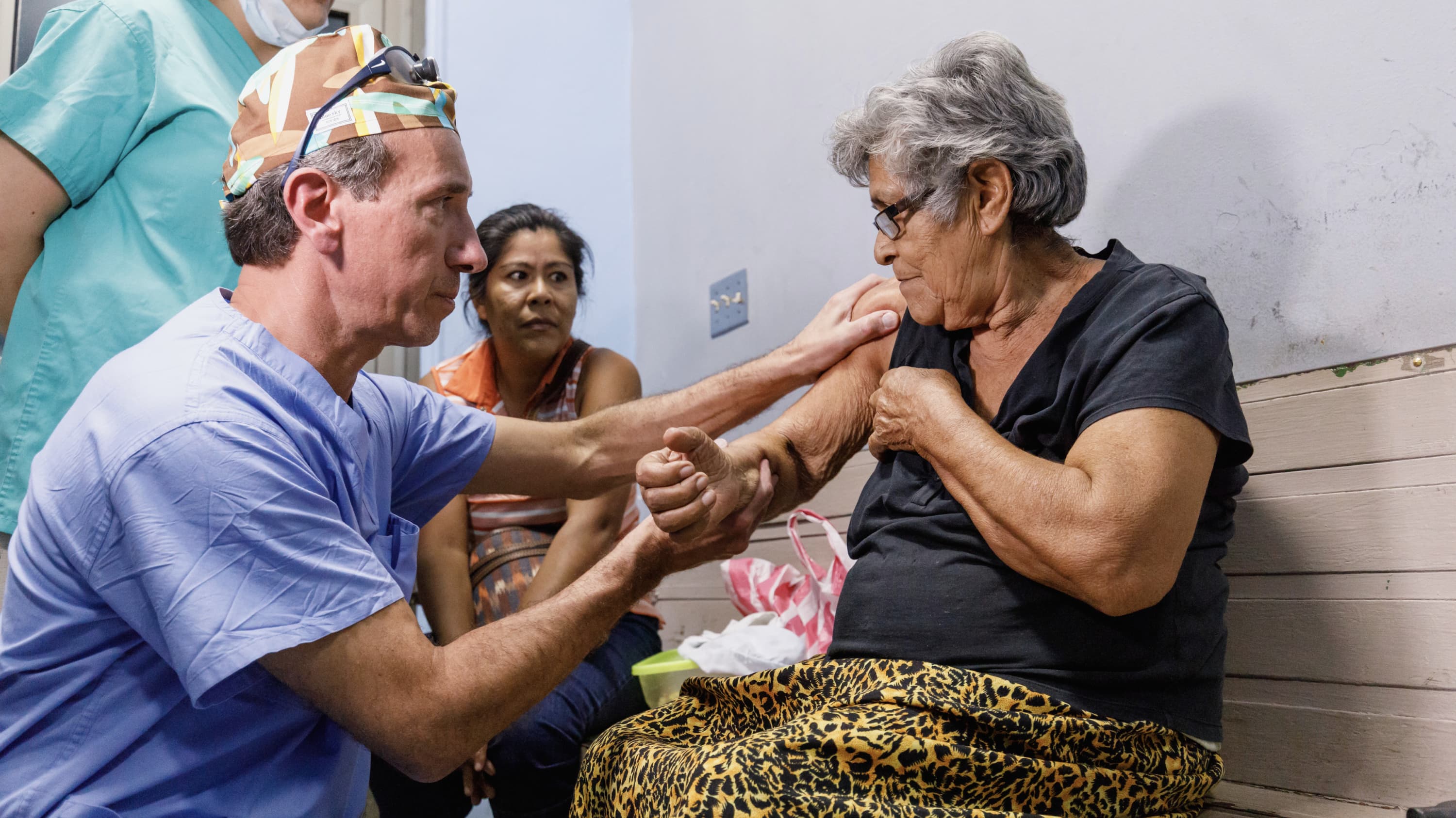 A doctor gently examines an elderly woman's arm and shoulder