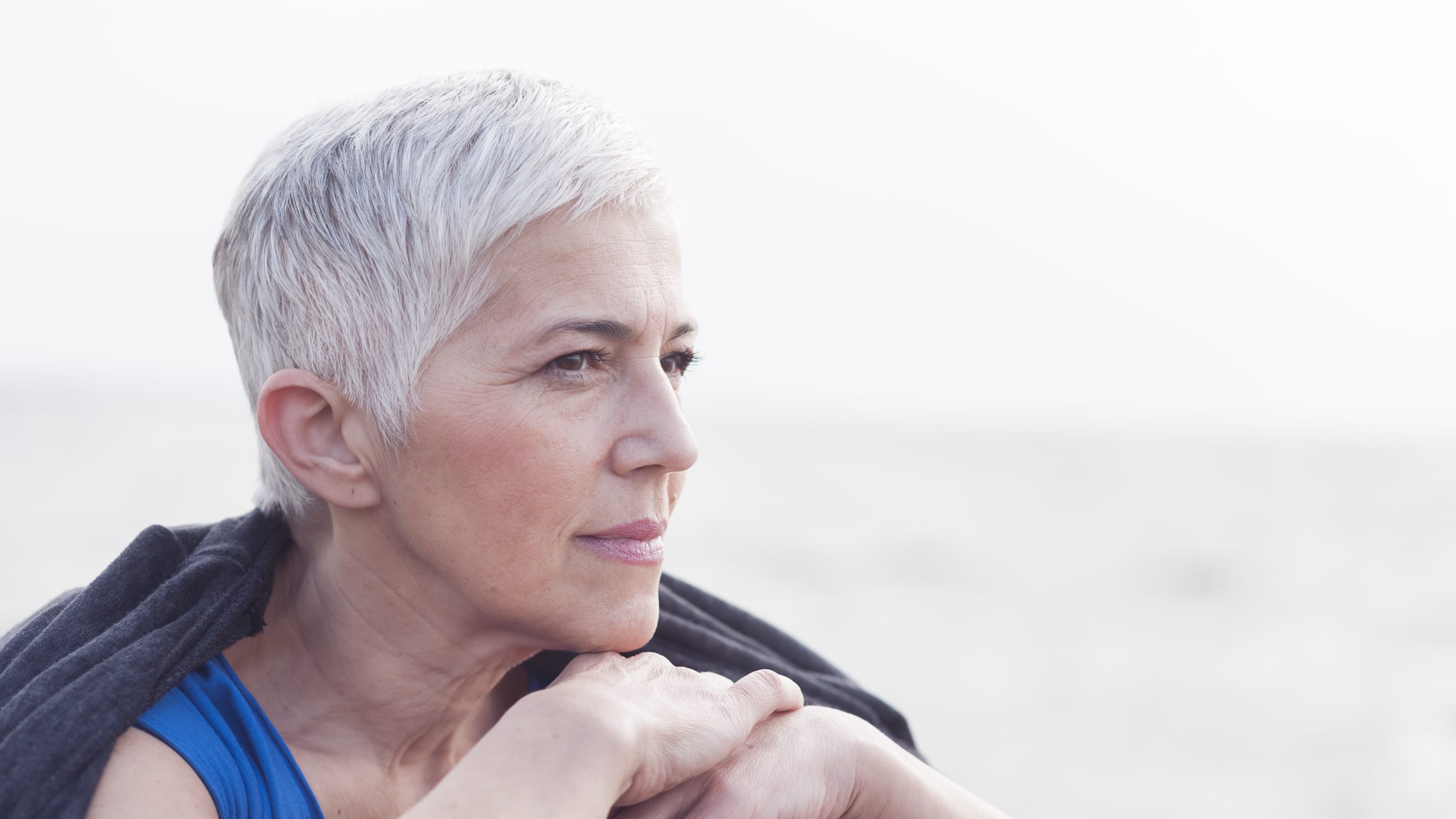 a woman with gray hair looks out at the water from a boat. she possibly has uveitis