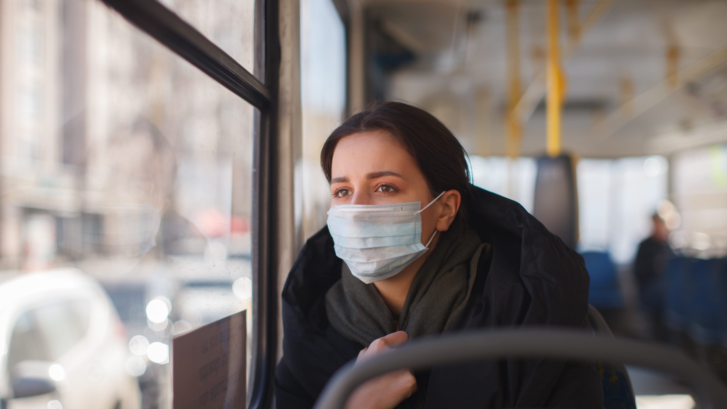 woman with facemask on a bus, worried about Omicron transmission