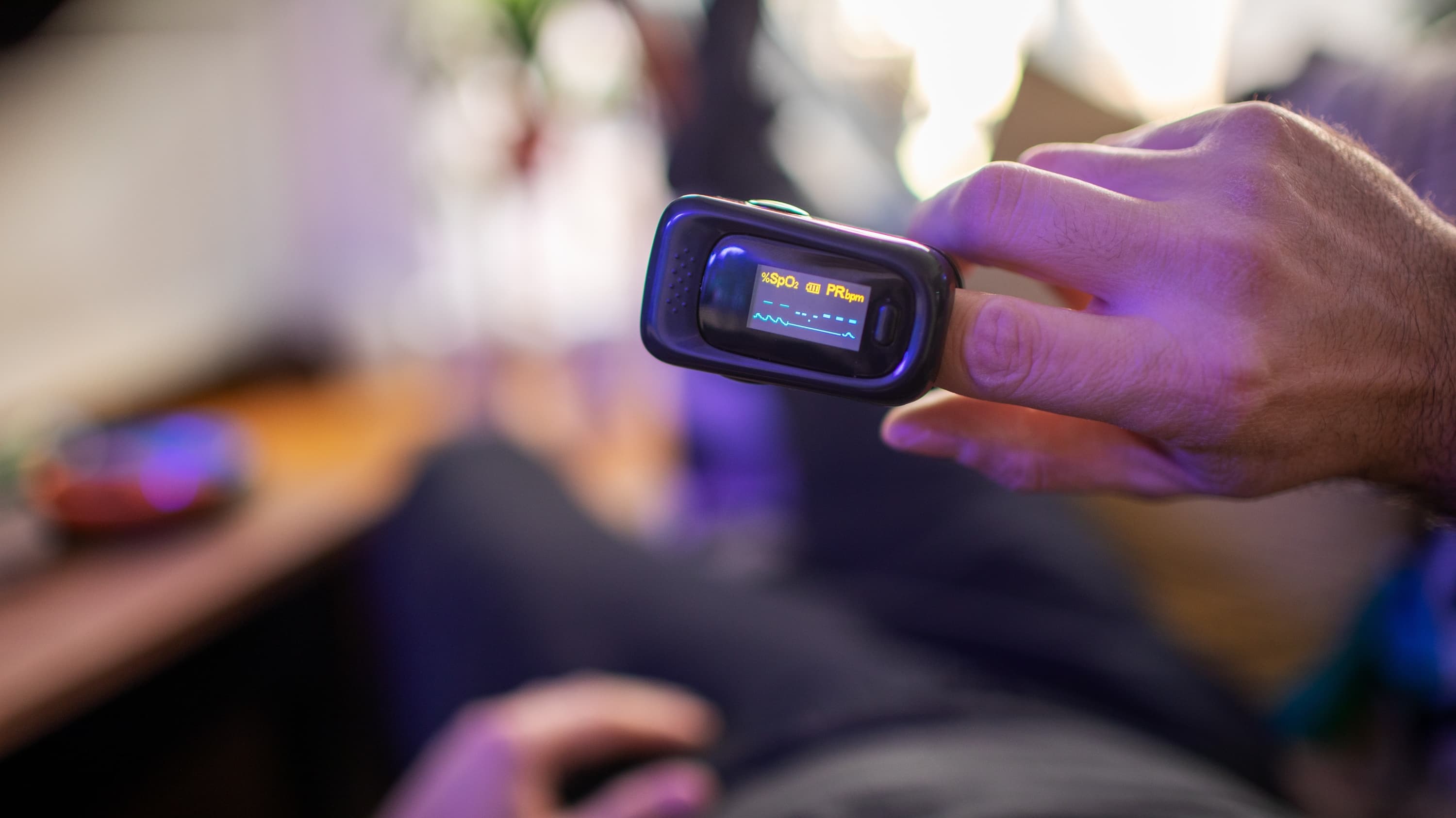 person with at-home pulse oximeter, possibly used to monitoring a COVID-19 symptom