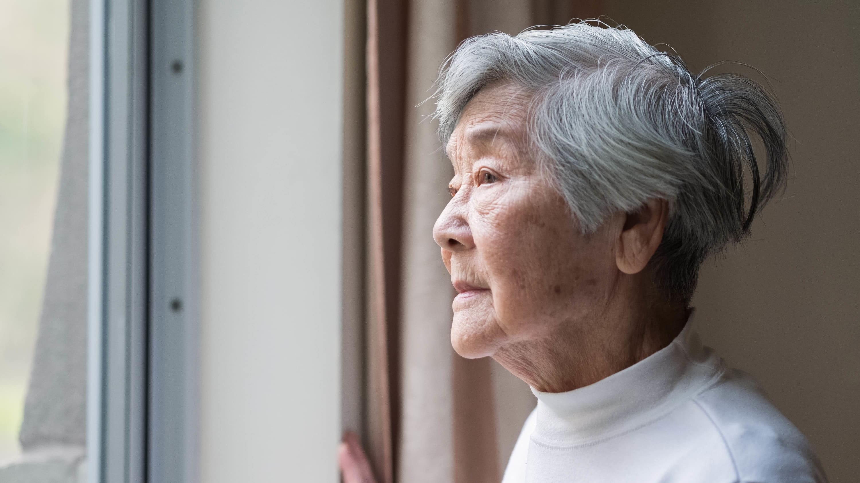 older woman, possibly with Alzheimer's disease, looking out window