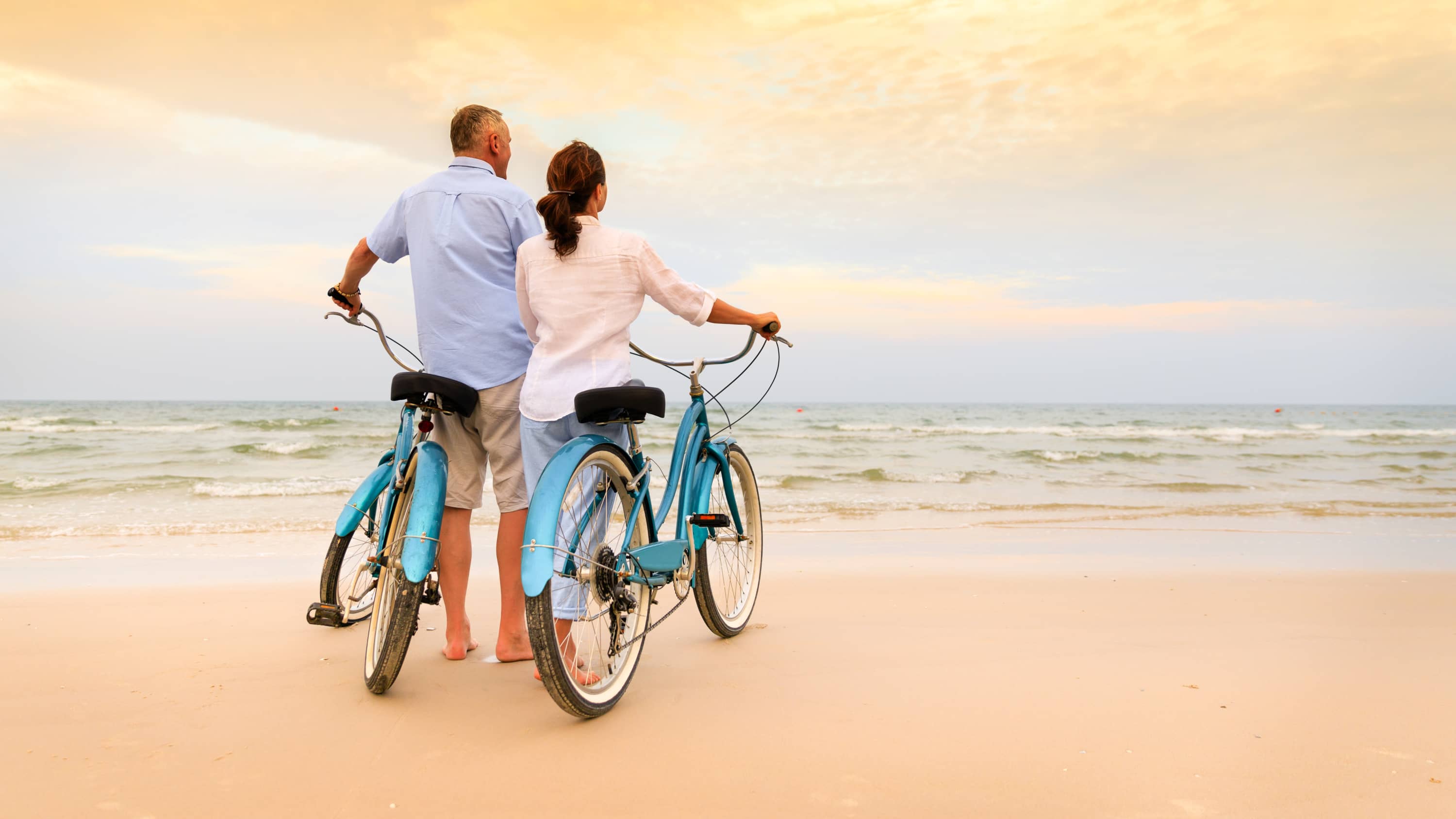 Couple on the beach with bikes, possibly after undergoing TAVR surgery