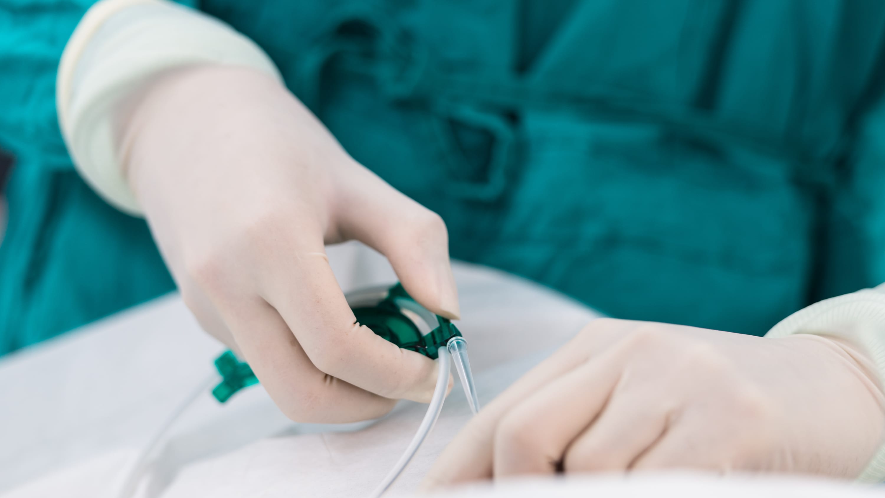 A nurse holding a piece of equipment during an endovascular brain surgery procedure.