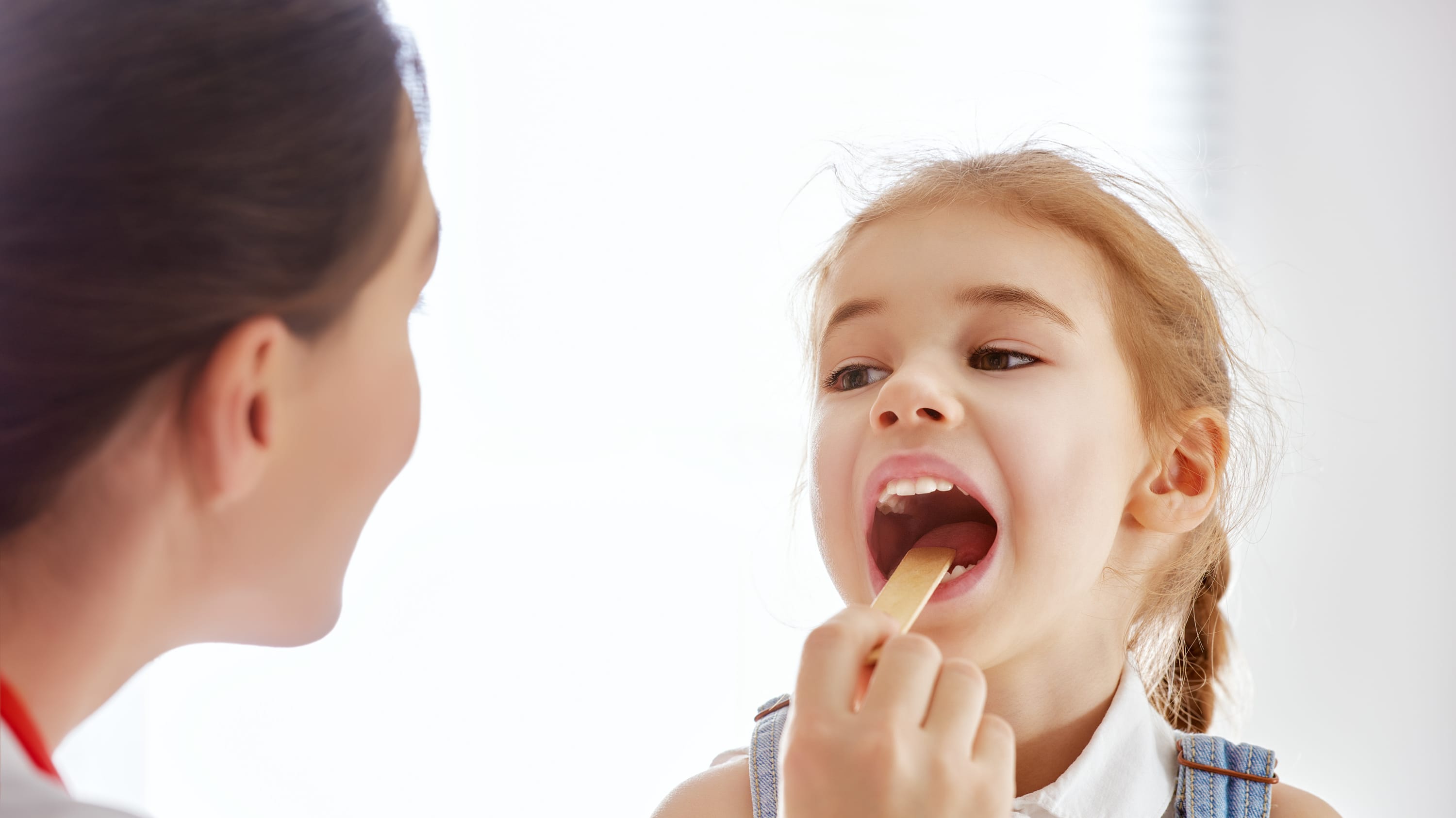 A girl has her throat examined for pediatric tonsillitis.