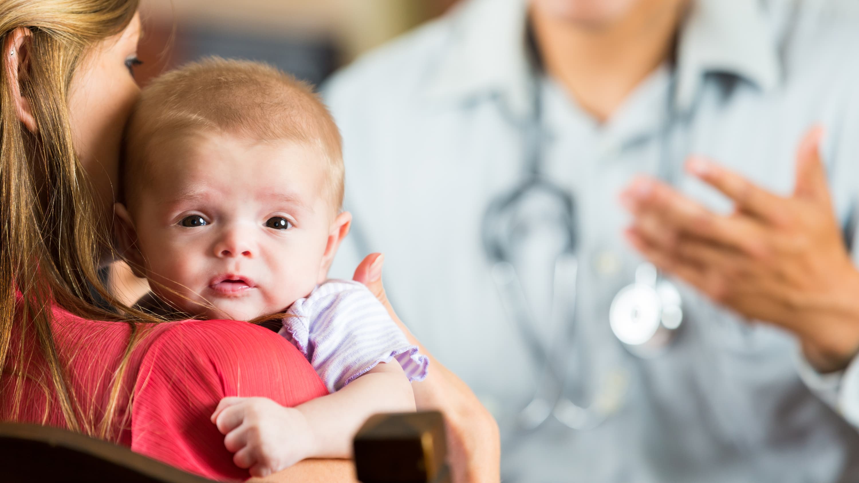 A baby with cystic fibrosis is comforted during a visit to the doctor.