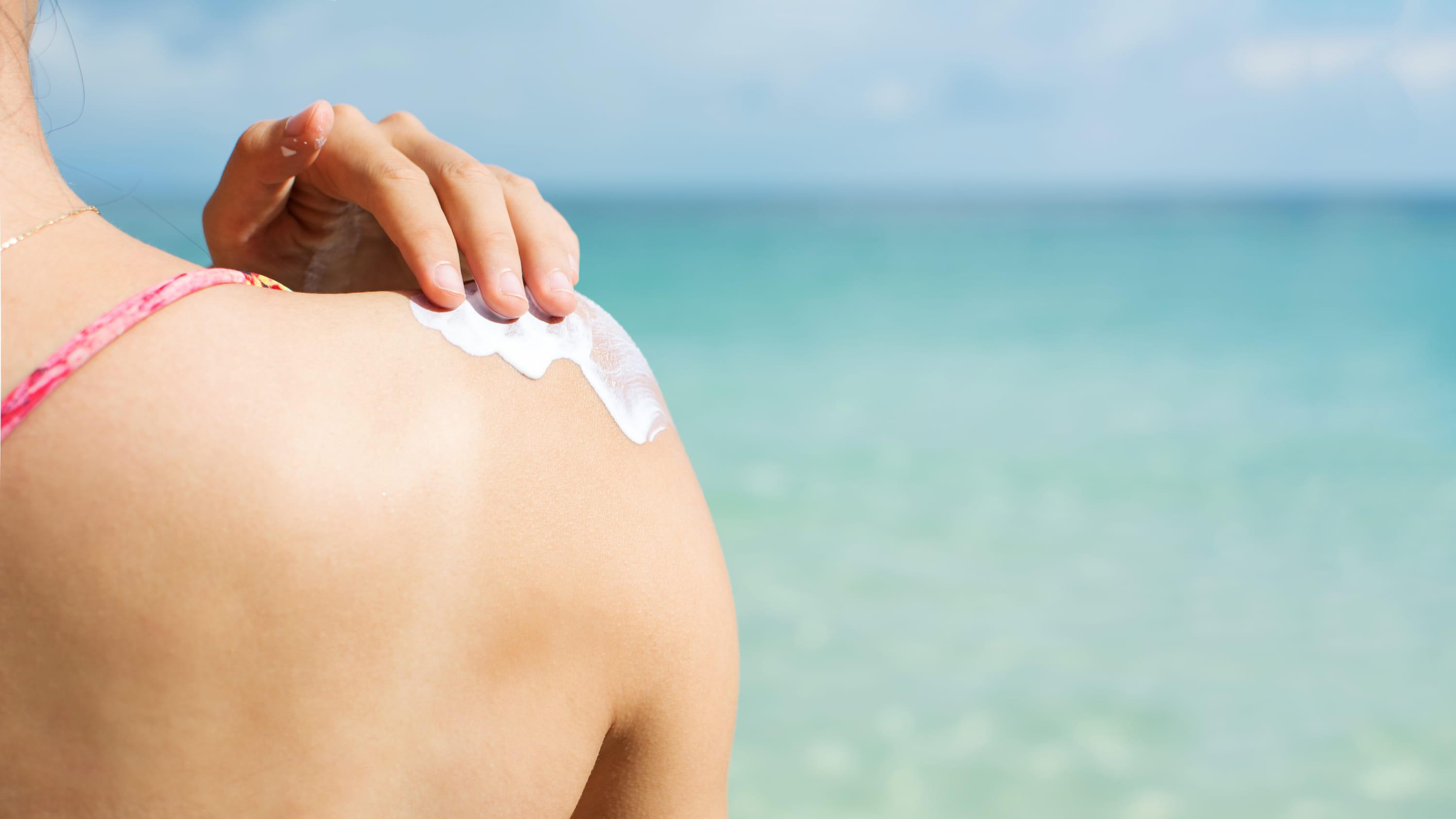 Girl applying sun lotion on the beach