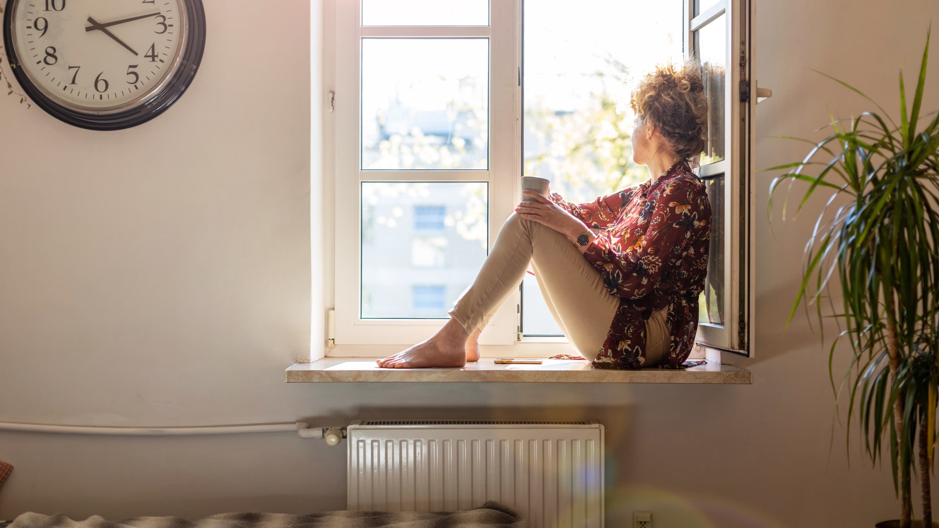 woman looking out window after coping with cancer side effects
