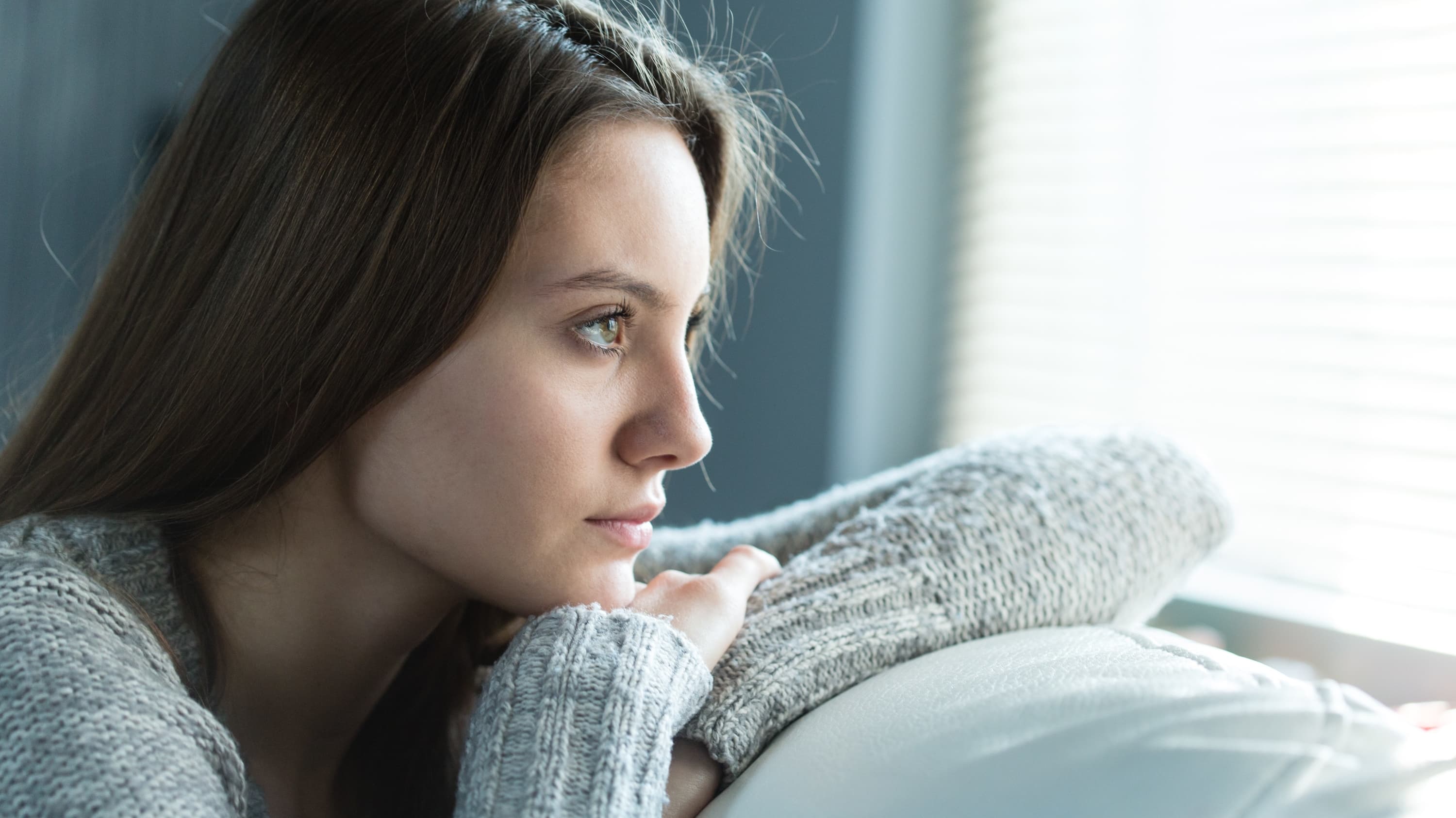 woman looking out window, possibly worried about vaginitis