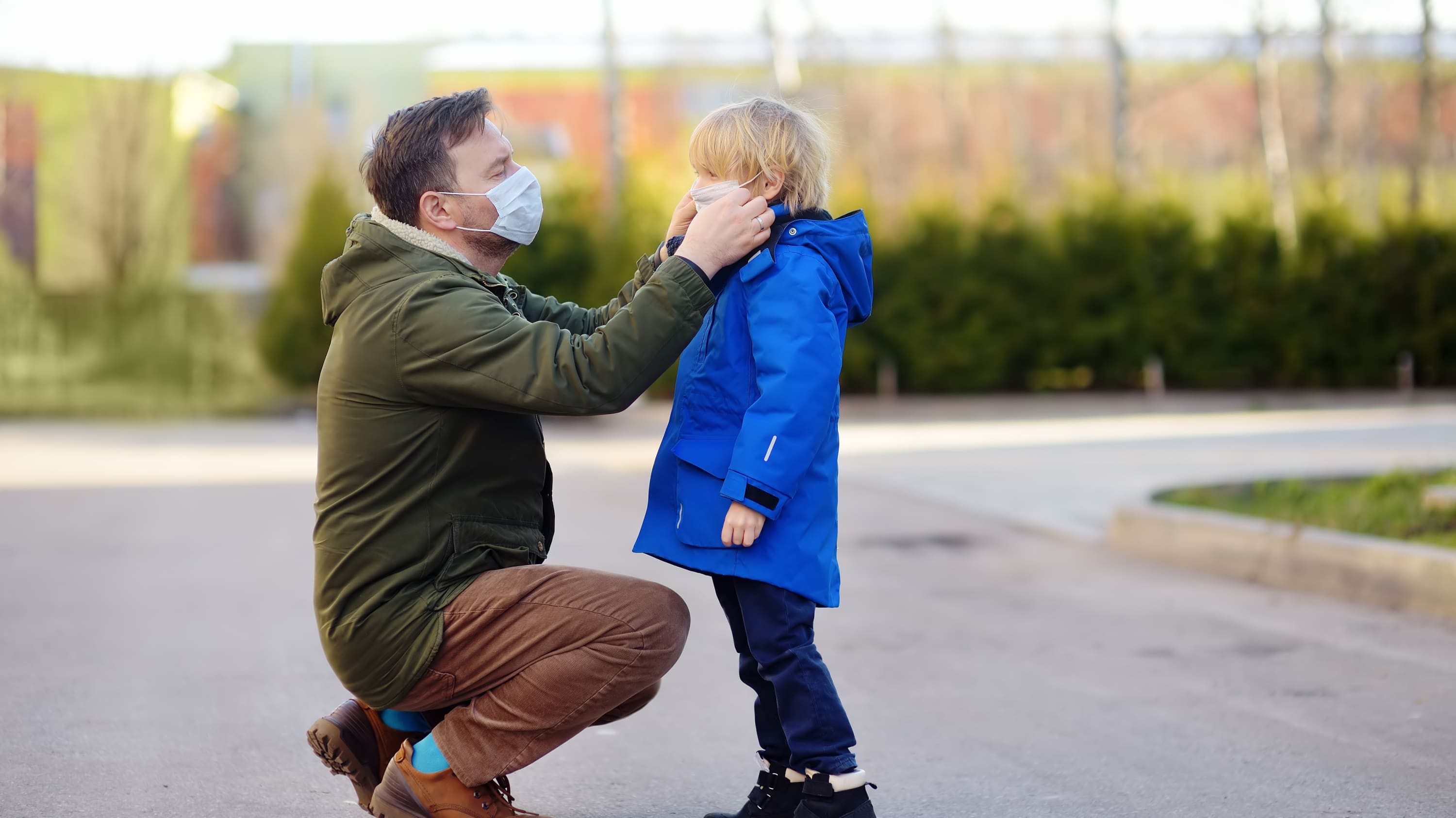 father putting face mask on son, possibly to protect against MIS-C, the syndrome in children associated with COVID-19